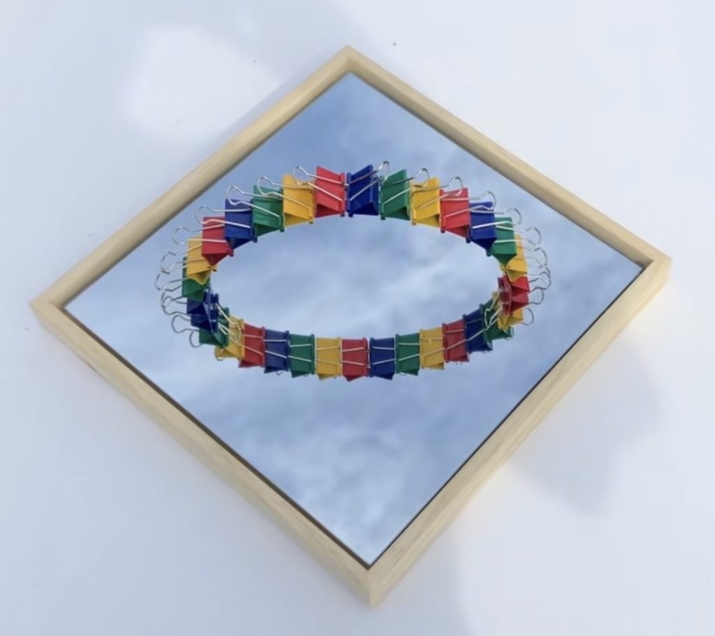 The Semicircle of document clips and the sky reflected in the mirror.
